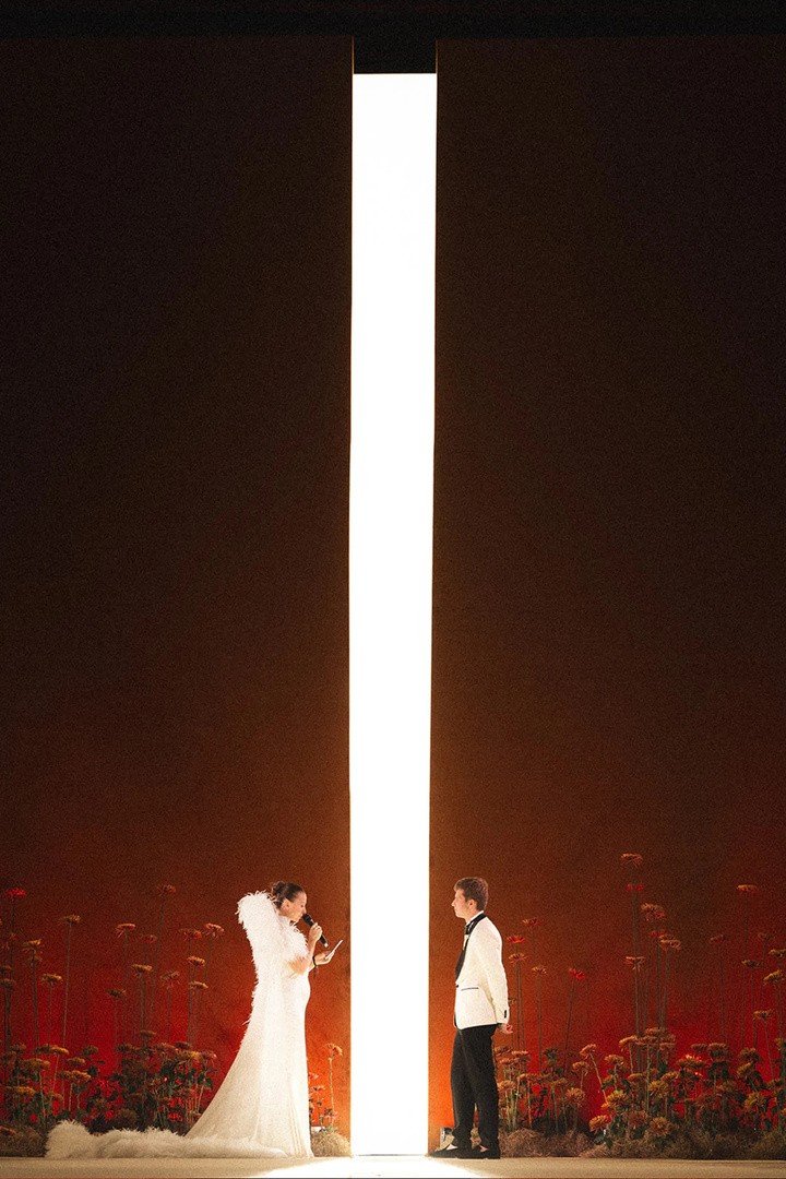 Reference: couple silhouetted by a light column amid red florals